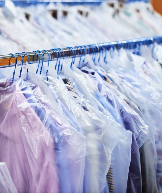 Abbildung verschiedene Kleidung in Schutzhüllen auf Kleiderbügeln und Kleiderstangen