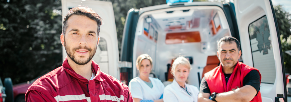 Abbildung vier Notfallsanitäter stehen vor einem Krankenwagen