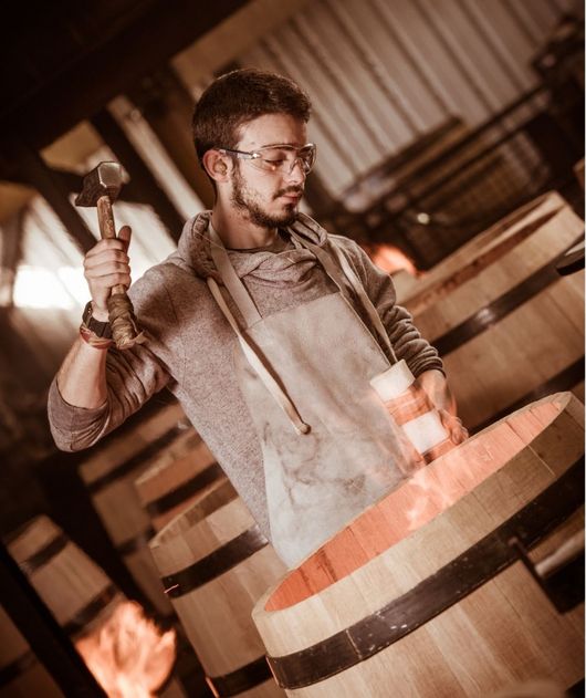 Abbildung Mann steht mit Hammer an einem Holzfass