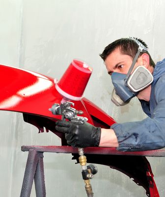 Abbildung Mann mit Gasmaske lackiert ein Autoteil mit roter Farbe 