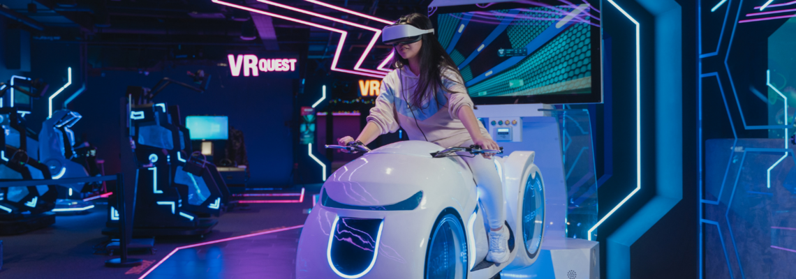 Abbildung eine Person sitzt mit einer VR-Brille auf einem virtuellen Motorrad 