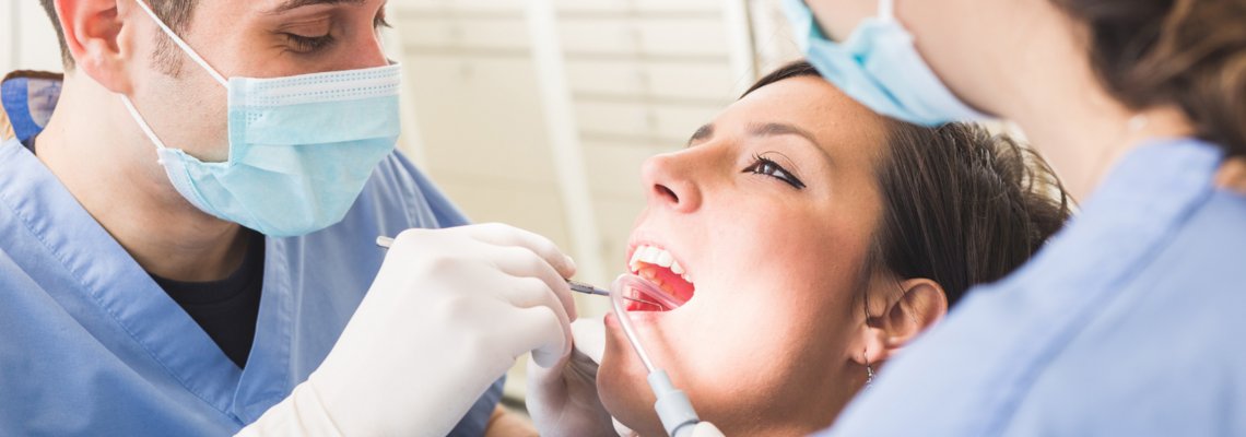 Abbildung zwei Ärzte mit Mundschutz die Zähne einer Patientin behandeln