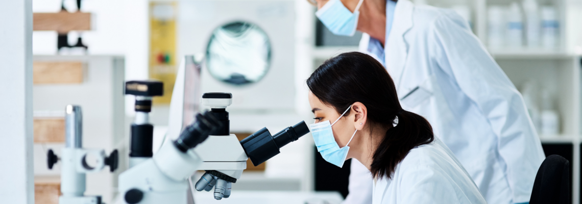 Abbildung zwei Laborarbeiterinnen schauen durch ein Mikroskop