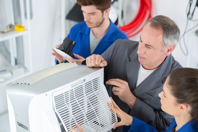 Abbildung Personen schauen auf eine Klimaanlage 
