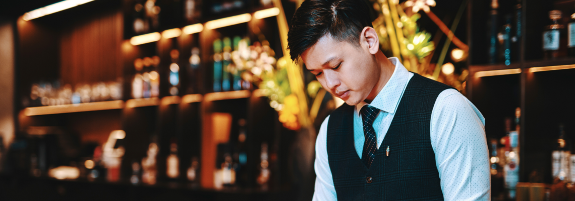 Abbildung ein edel gekleideter junger Mann mischt einen Cocktail an einer Bar