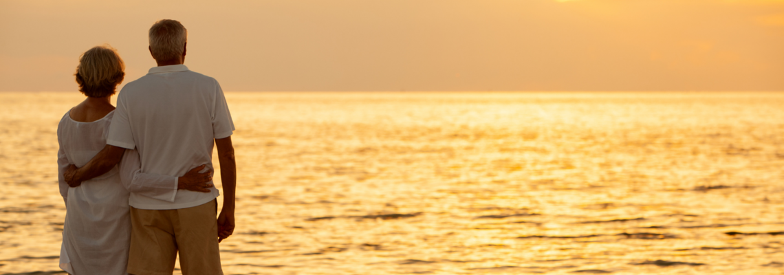 Abbildung Pärchen schaut sich am Meer einen Sonnenuntergang an 