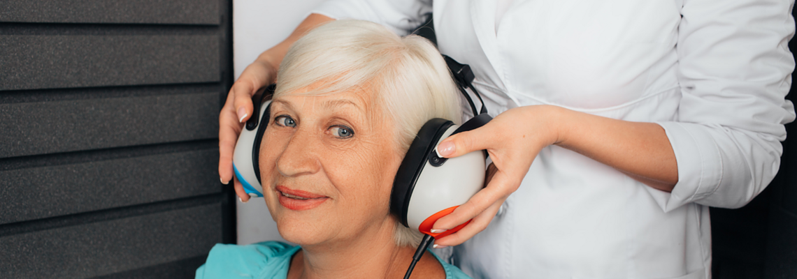 Abbildung Eine ältere Frau mit großen Kopfhörer speziell für Hörtests 