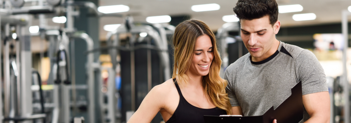 Abbildung ein Mann zeigt einer Frau seinen Trainingsplan im Fitnessstudio 