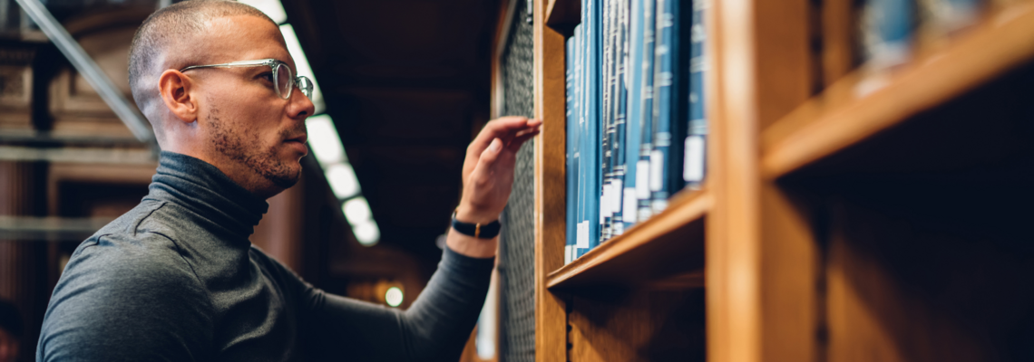 Abbildung ein Mann steht vor einem Bücherregal in einer Bibliothek