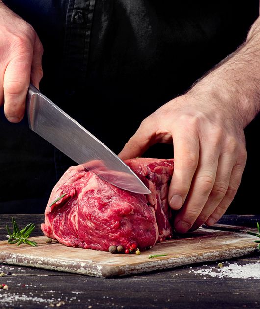 Abbildung Person schneidet eine Scheibe von einem Fleischstück herunter