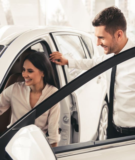 Abbildung Frau sitzt im weißen Auto, Mann steht in der offenen Autotür