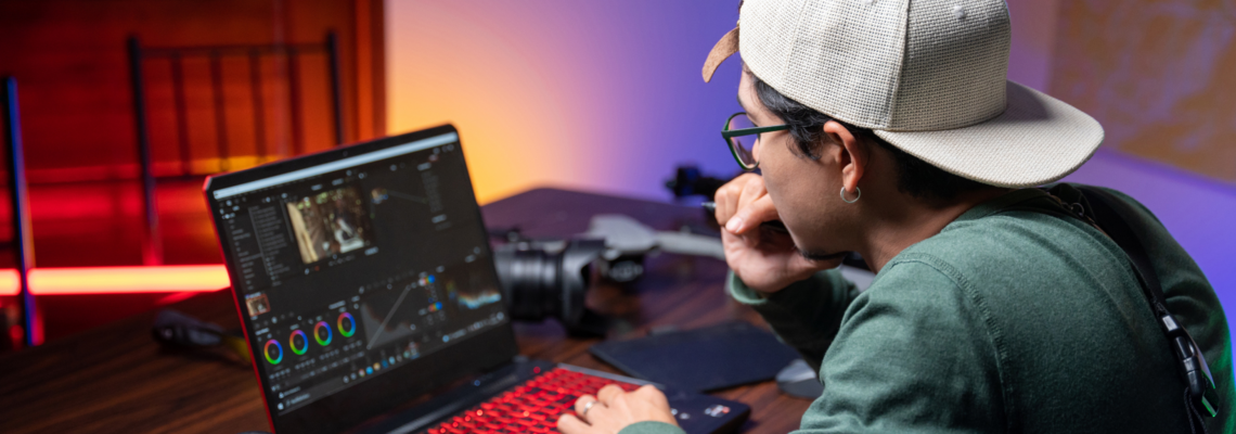 Abbildung ein Mann bearbeitet Videos auf einem Laptop neben ihm liegt eine Kamera