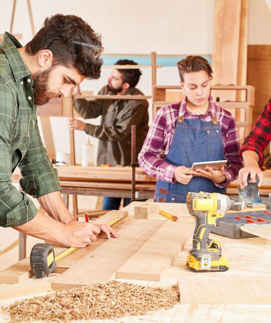 Abbildung drei Personen arbeiten mit Holz in einer Werkstatt