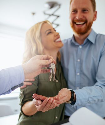 Abbildung Person übergibt Wohnungsschlüssel an einem Mann und eine Frau