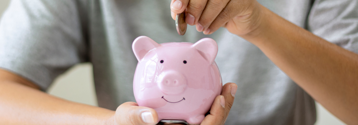 Abbildung Mensch mit grauem T-Shirt wirft eine Geldmünze in ein rosanes Sparschwein