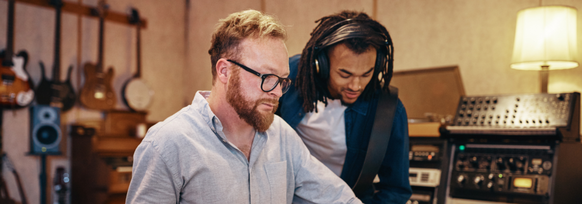 Abbildung zwei Männer stehen in einem Musikstudio und hören etwas an 
