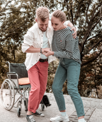 Abbildung Frau hilft jungen Mann aus dem Rollstuhl
