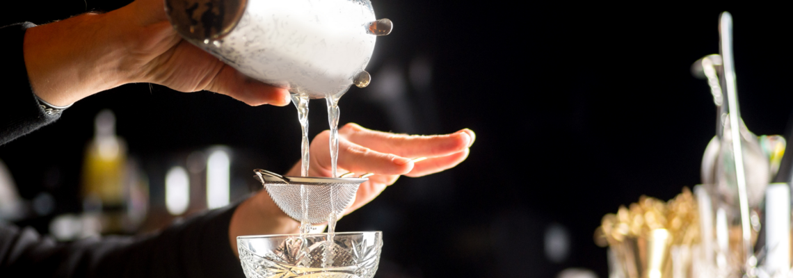 Abbildung ein Cocktail wird aus einem Shaker in ein Glas abgegossen