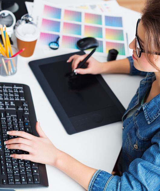 Abbildung Junge Frau mit Brille arbeitet mit einer Tastatur und einem Scanner