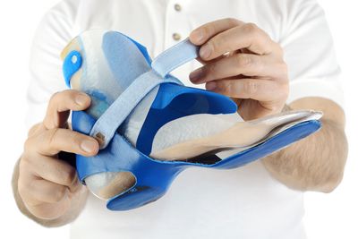 Abbildung Mann präsentiert eine Sprunggelenksbandage an einem Fußmodell