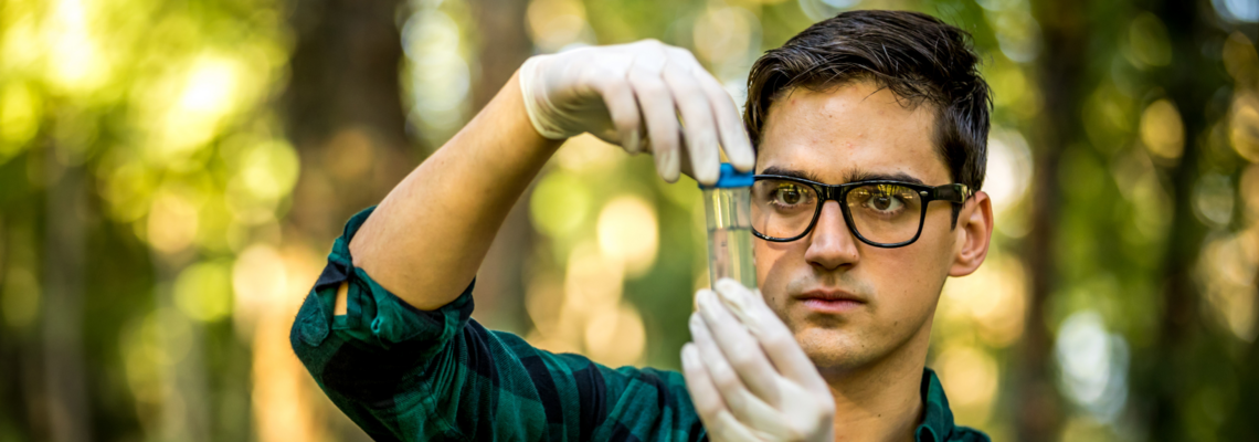 Abbildung ein Mann im Wald untersucht eine Flüssigkeit in einem Reagenzglas