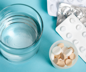 Abbildung Wasserglas mit verschiedenen Medikamenten in Tablettenform