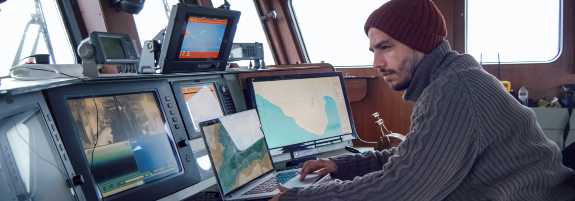 Abbildung ein Mann sitzt in einem Schiff vor Bildschirmen mit Orientierungsanzeigen 