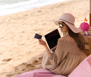 Abbildung junge Frau sitzt mit einem Laptop an einem Strand