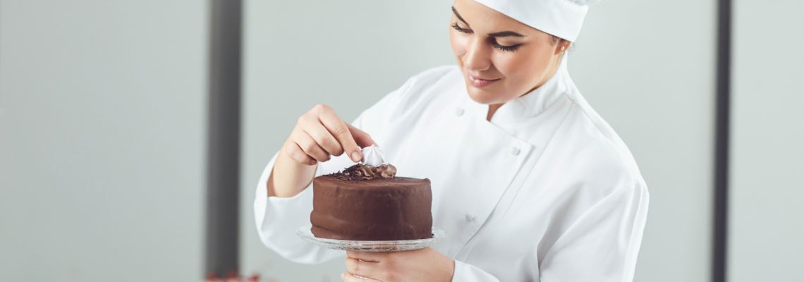 Abbildung Konditorin verziert einen Schokoladenkuchen mit Sahne