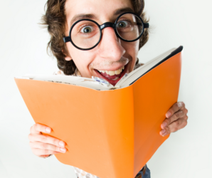 Abbildung junger Mann mit Brille schaut hinter einem Buch hervor 