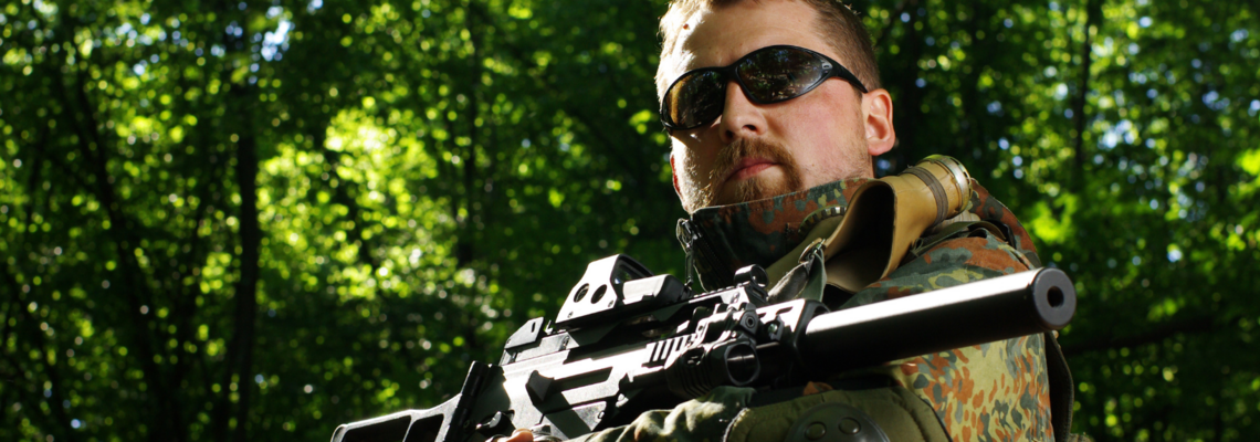Abbildung Soldat mit einer Sonnenbrille und einer Waffe im Wald 