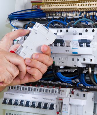 Abbildung zwei Hände bauen einen FI Schalter in einem Stromkasten ein