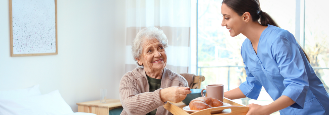 Abbildung Ältere Dame nimmt Essenstablett von einer jungen Pflegerin entgegen 